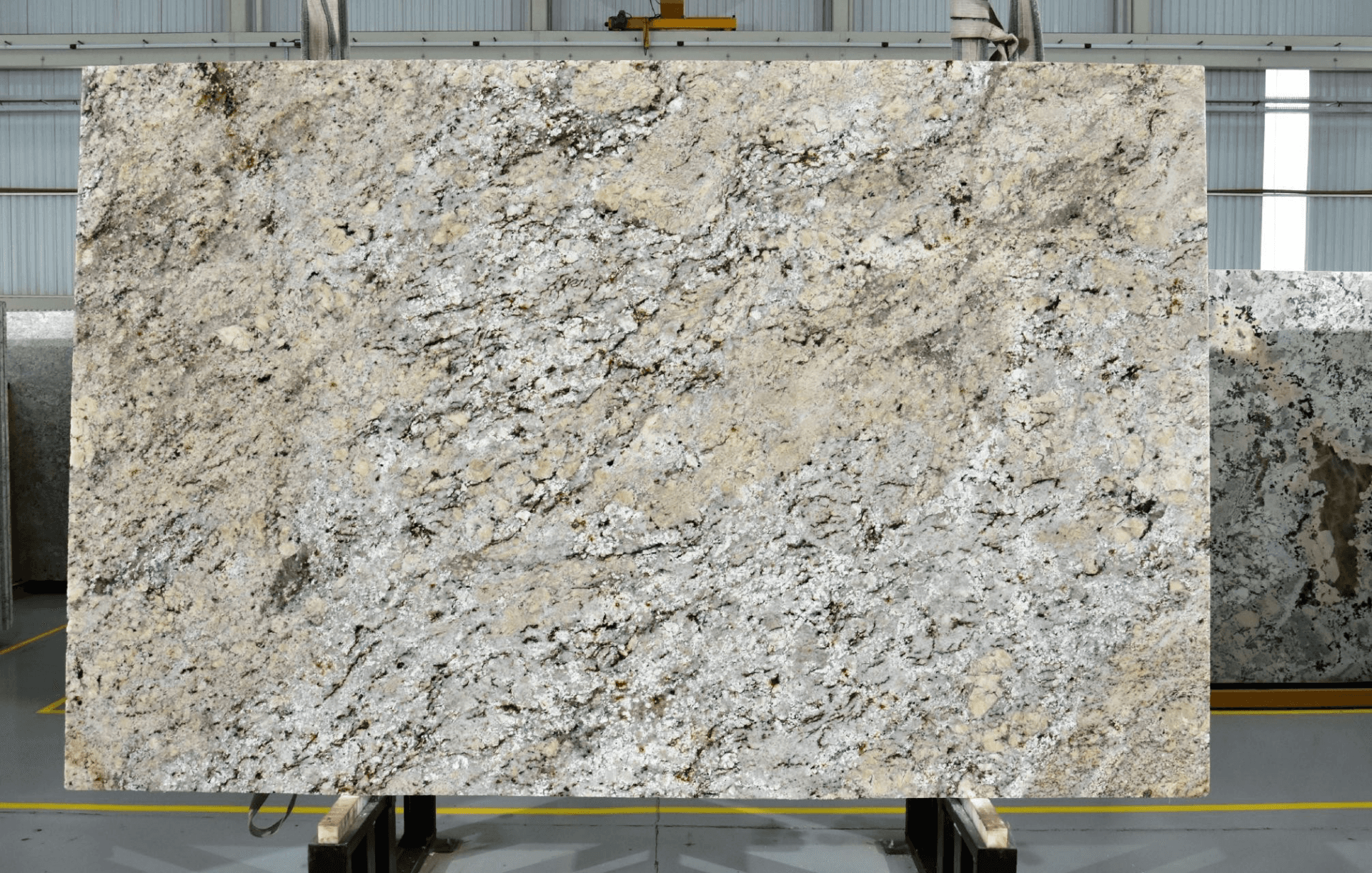 A beige and gold granite slab standing on the rack at the shop